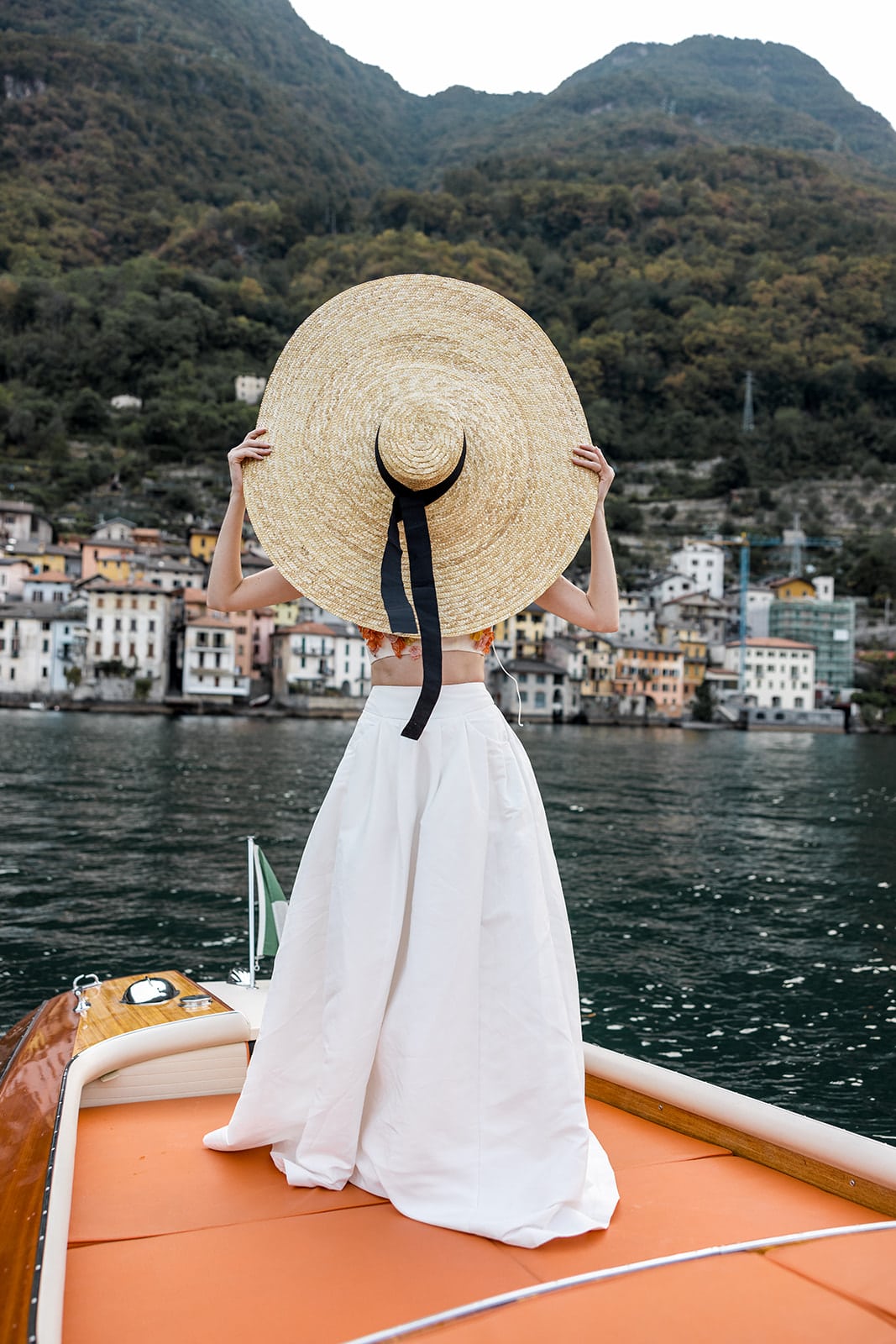 Bride wears a large sunhat on a boat on Lake Como