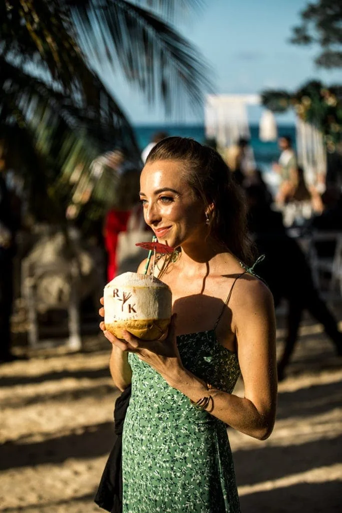 A bridesmaid sips from a coconut at a destination wedding in Jamaica