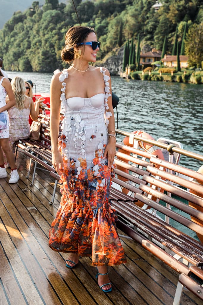 Woman wearing couture dress stands on deck of boat on Lake Como the day before her wedding. 