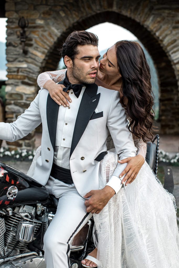Bride and groom, wearing white tuxedo ideas, on motorcycle