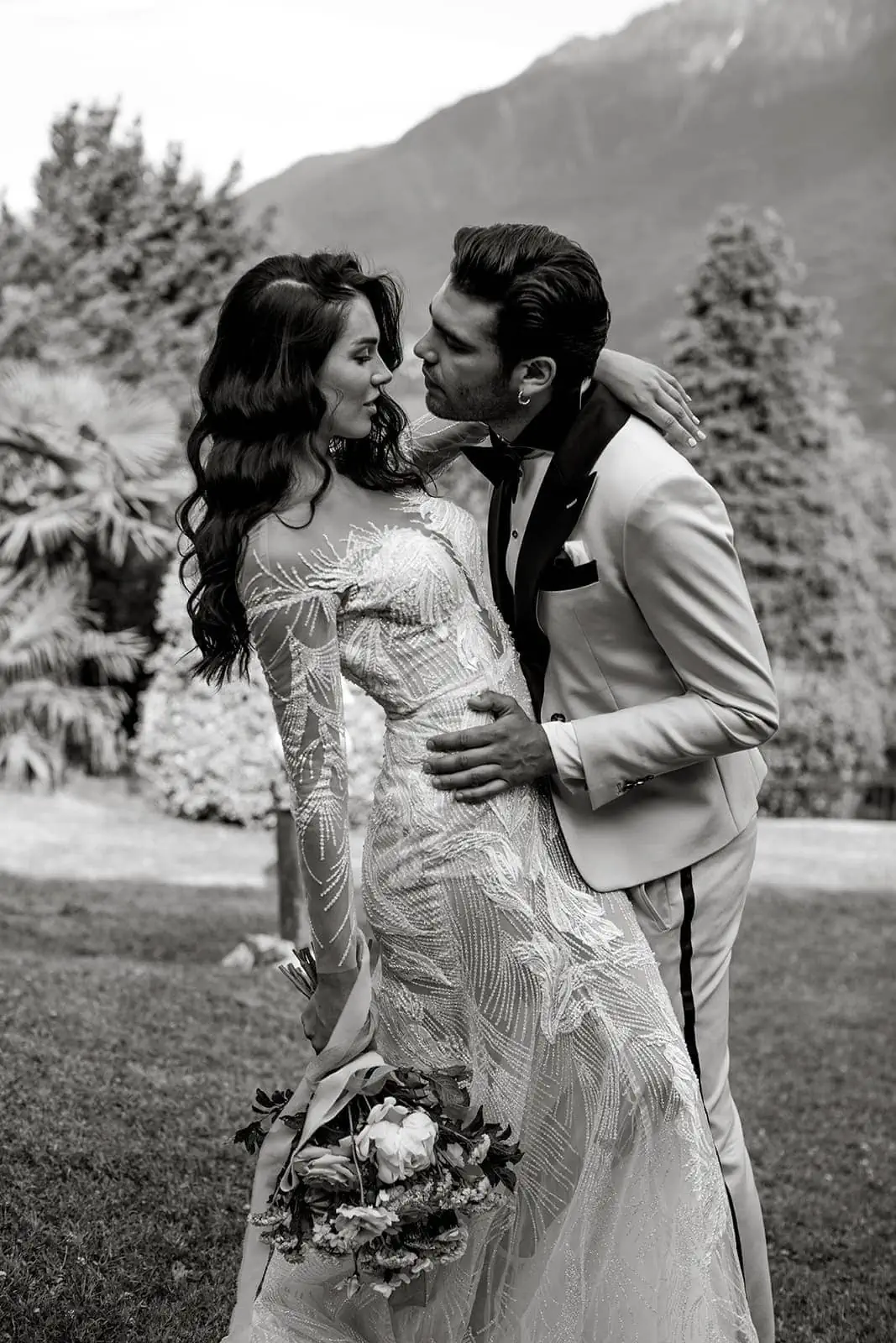 Groom embraces bride in Lake Como