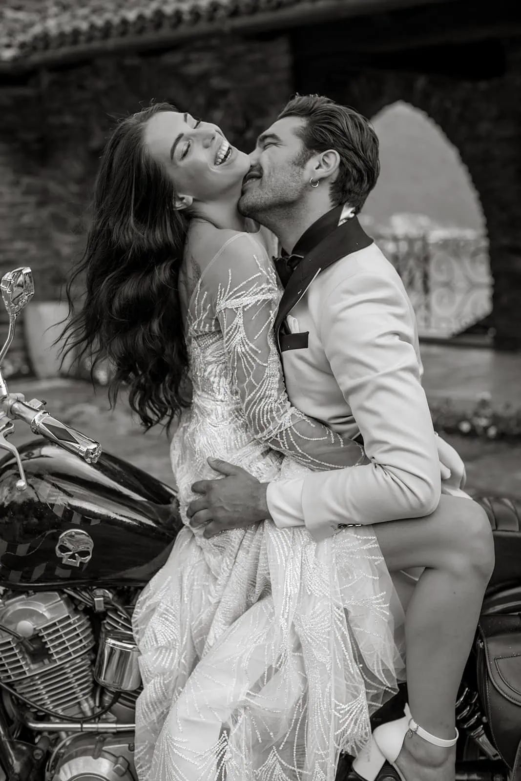 Groom kisses bride on motorcycle