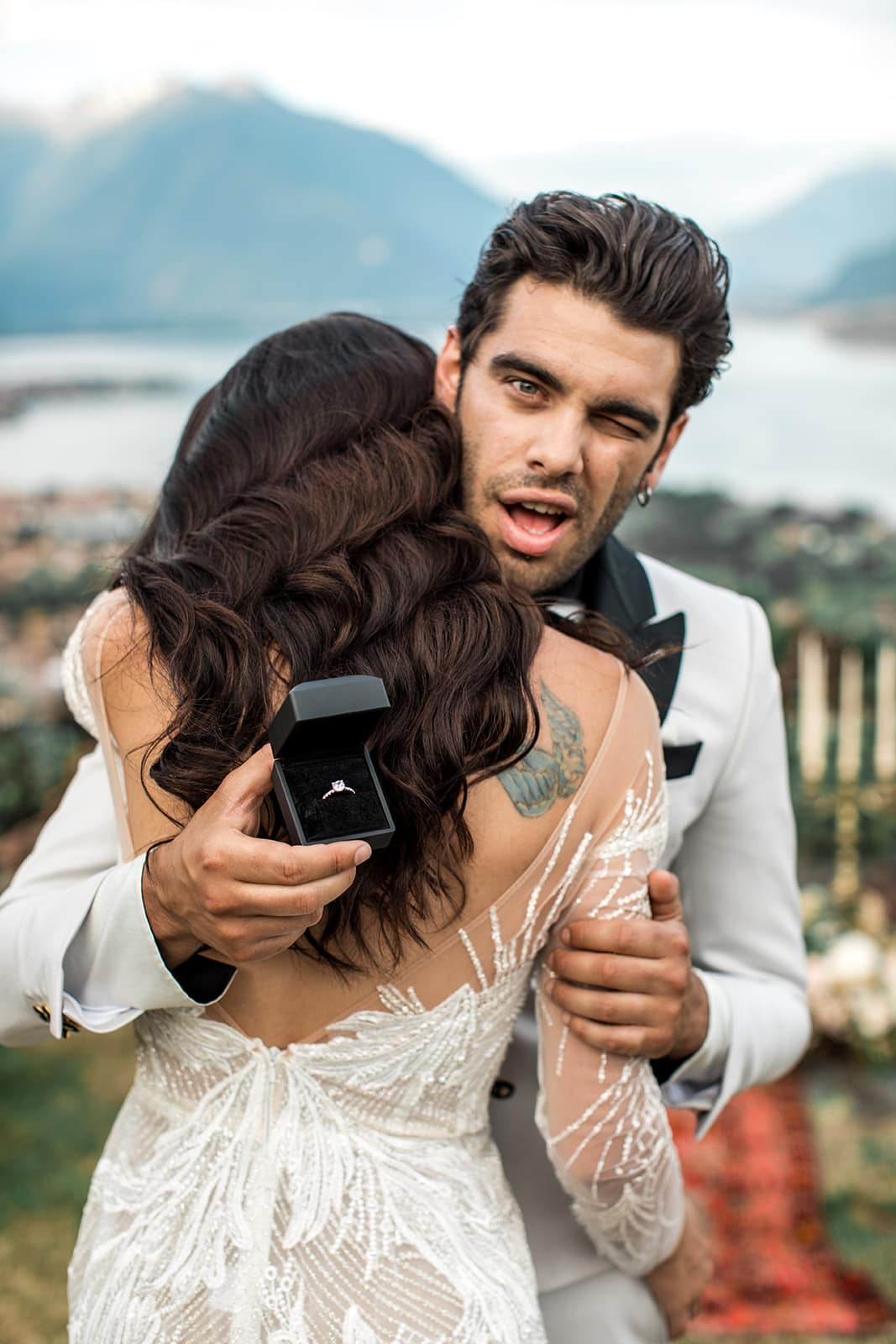 Groom shows ring to camera behind bride's back