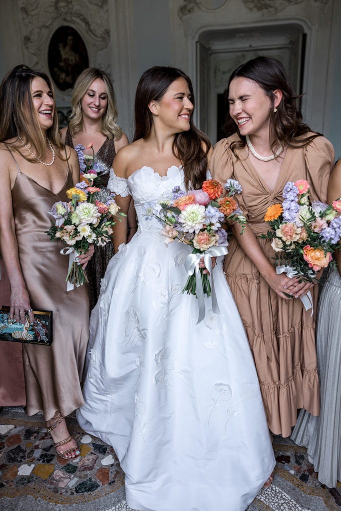 Bride and bridesmaids hold bright, poppy bouquets