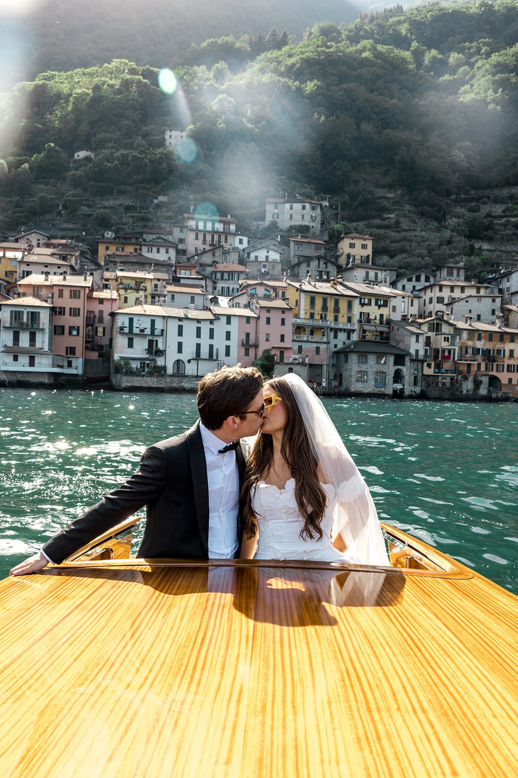 Bride and groom kiss on riva boat in Lake Como, Italy