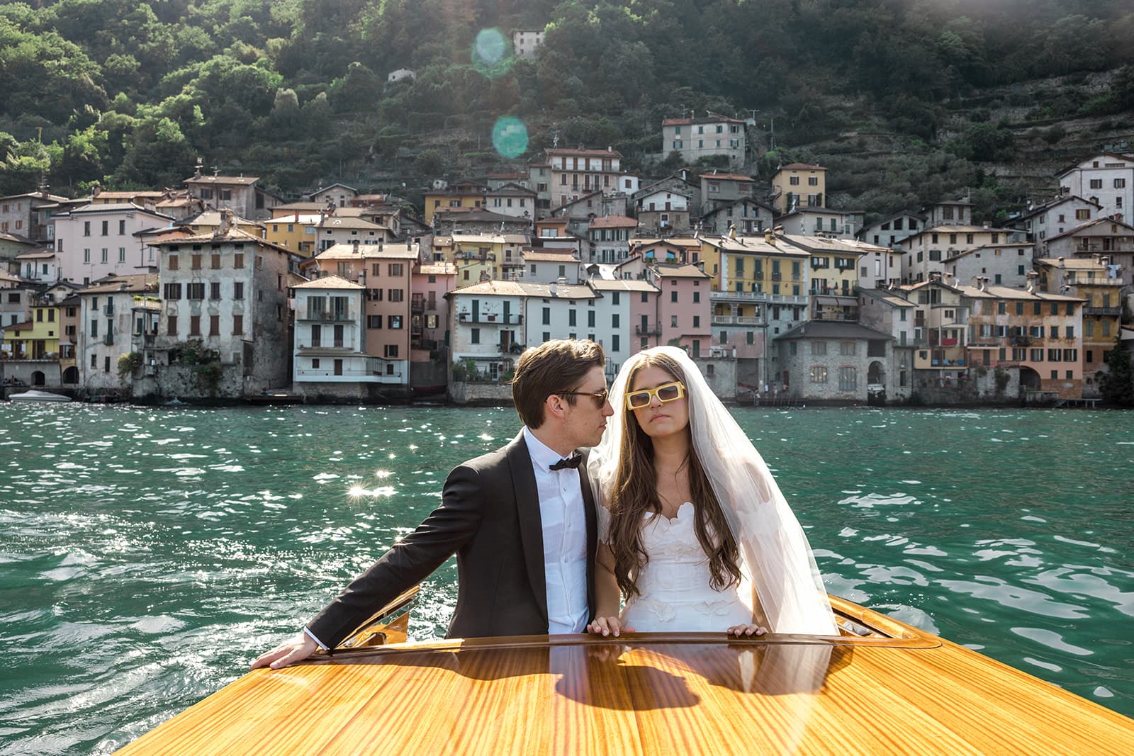 Groom looks at bride as they ride in classic Riva on Lake Como