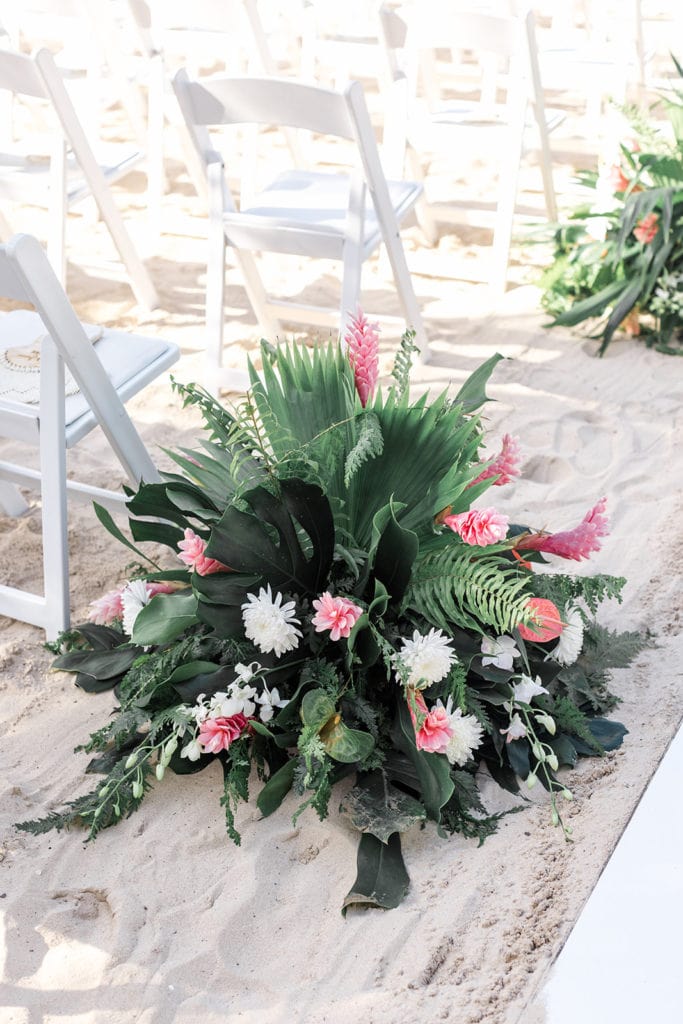 Floral arrangement is an aisle marker for a beach wedding