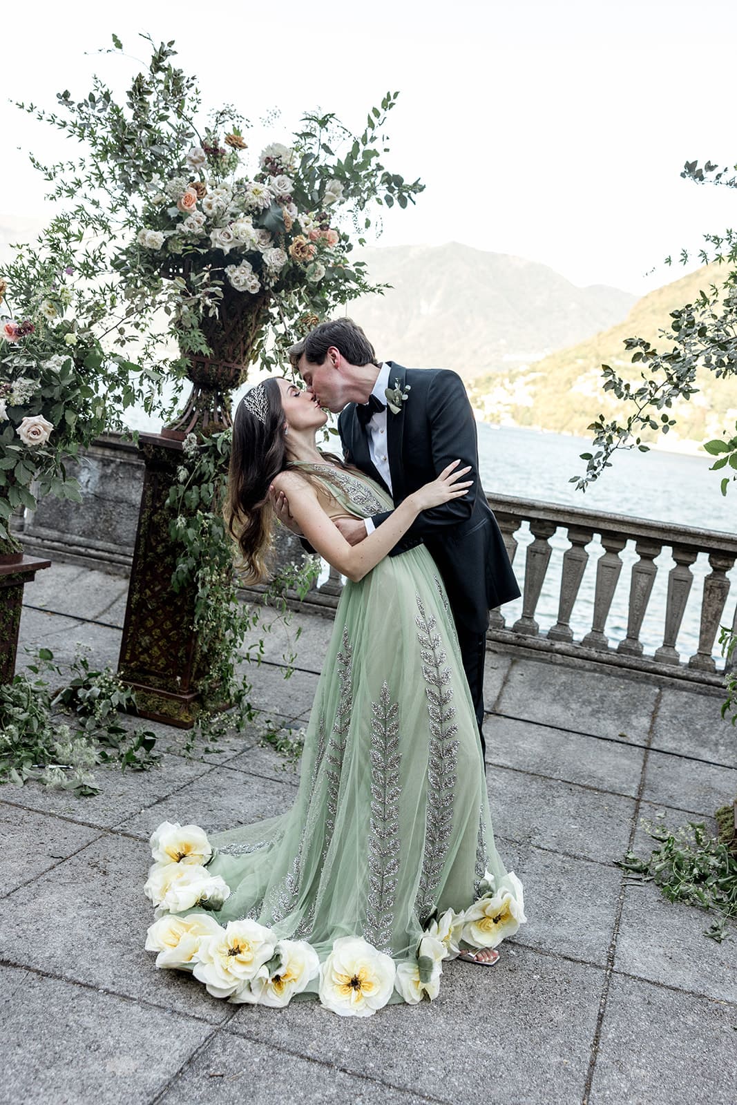 Groom kisses bride with a view of Lake Como in the background
