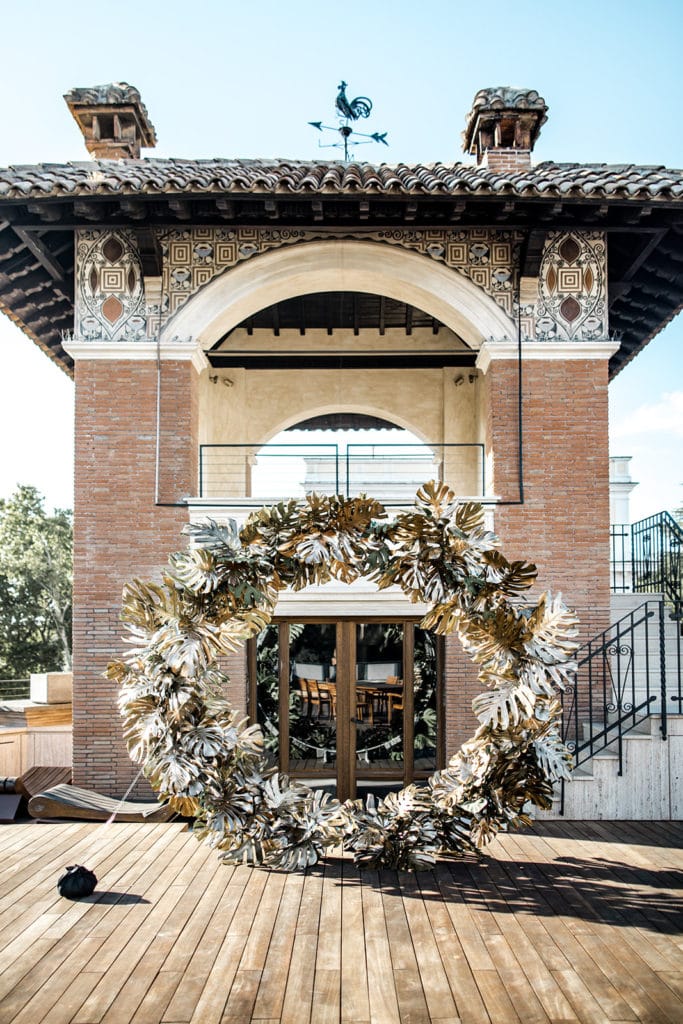 A circular arch made of golden palm fronds stands at a ceremony site at the Villa Clara in Rome