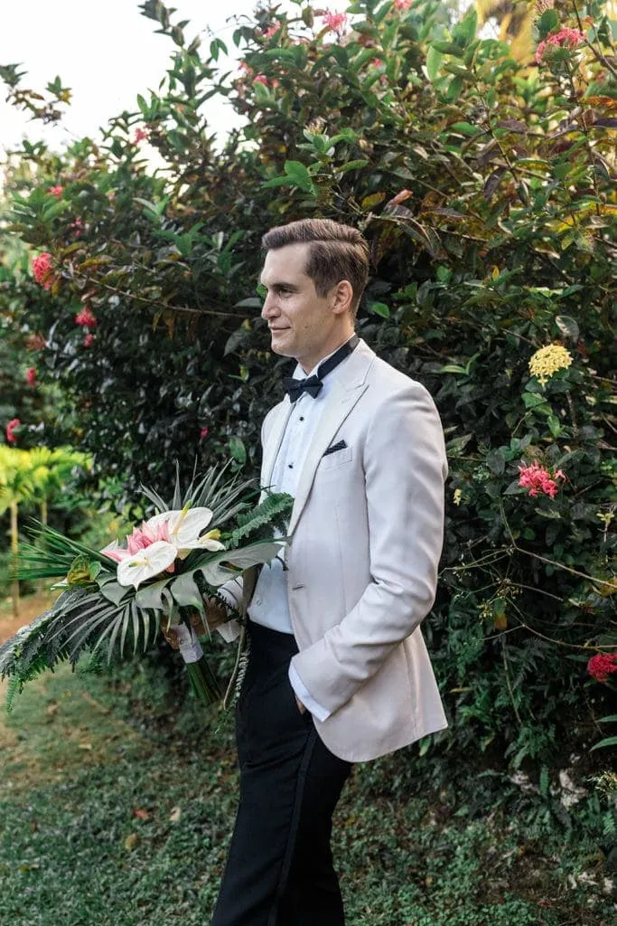 Groom waits on bride while holding her bridal bouquet
