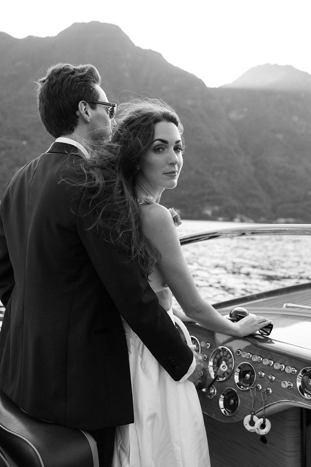 Groom hugs bride on a boat on Lake Como