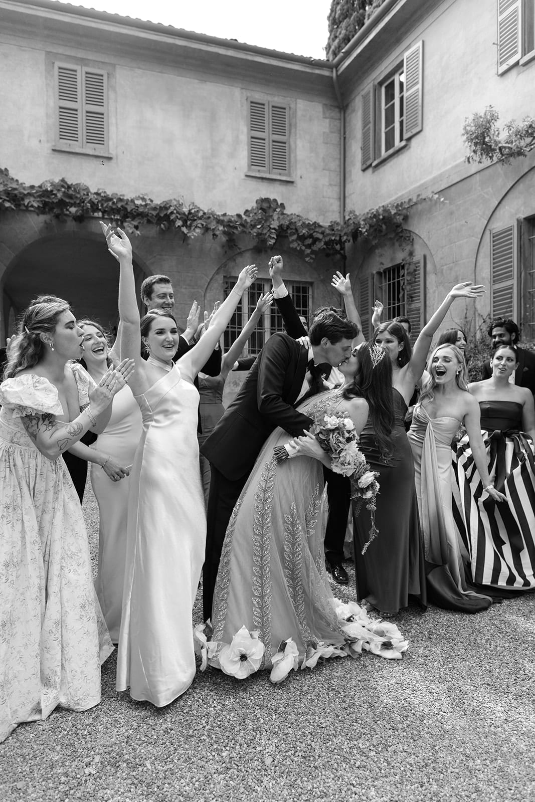 Groom kisses bride while bridal party cheers at a Lake Como wedding villa