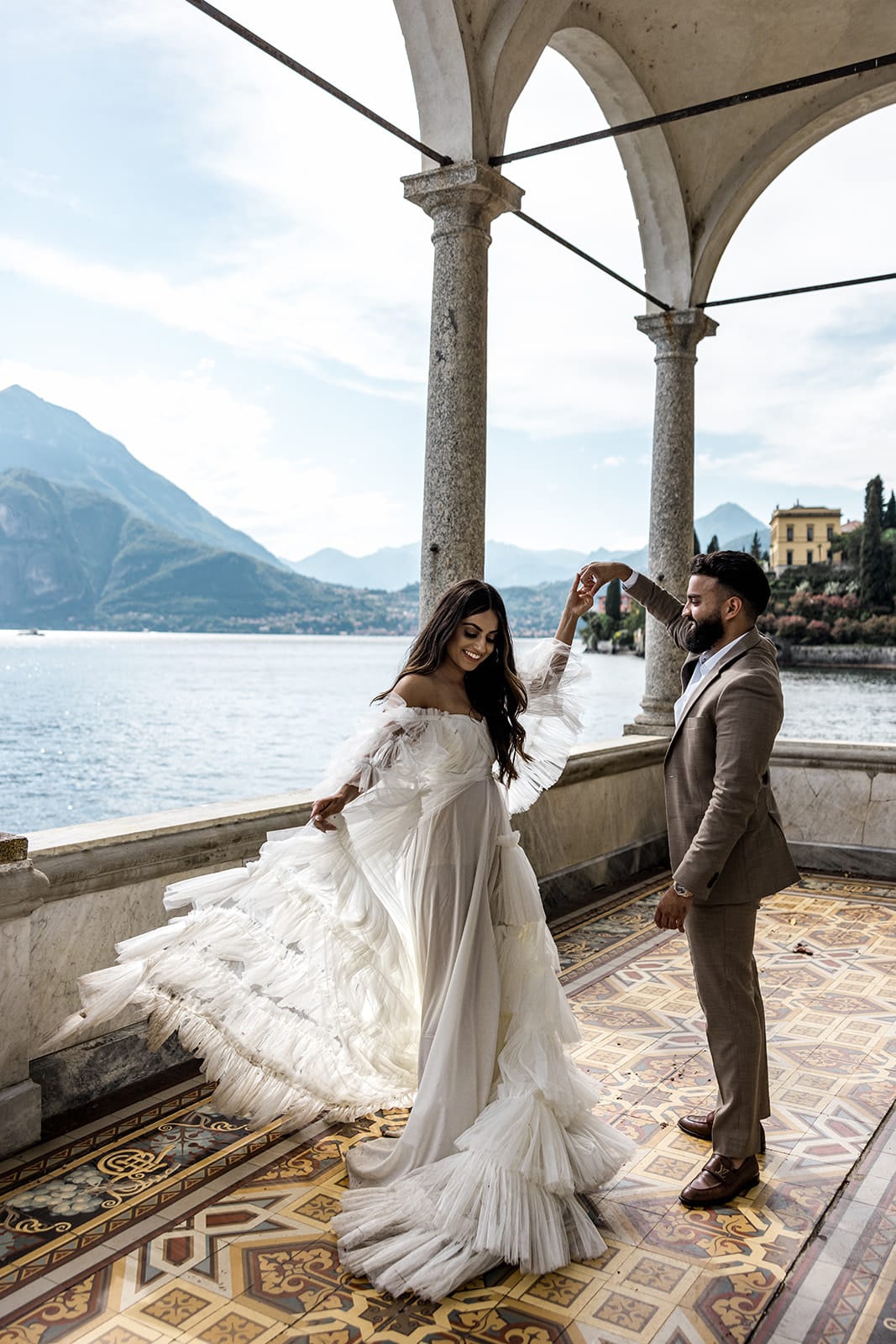 Man twirls woman with view of Lake Como in background