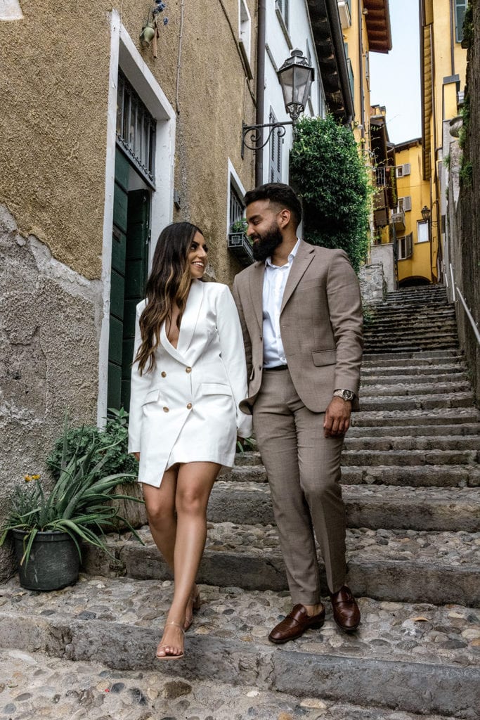 Man and woman walking streets of Varenna with local Lake Como engagement photographer, after learning the purpose of engagement photos