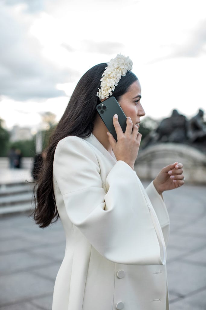 Bride holds cell phone to ear as she walks through streets of London
