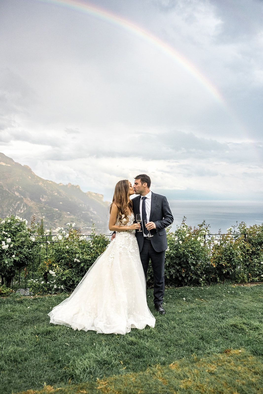 Bride and groom kiss in Ravello Italy with rainbow in background