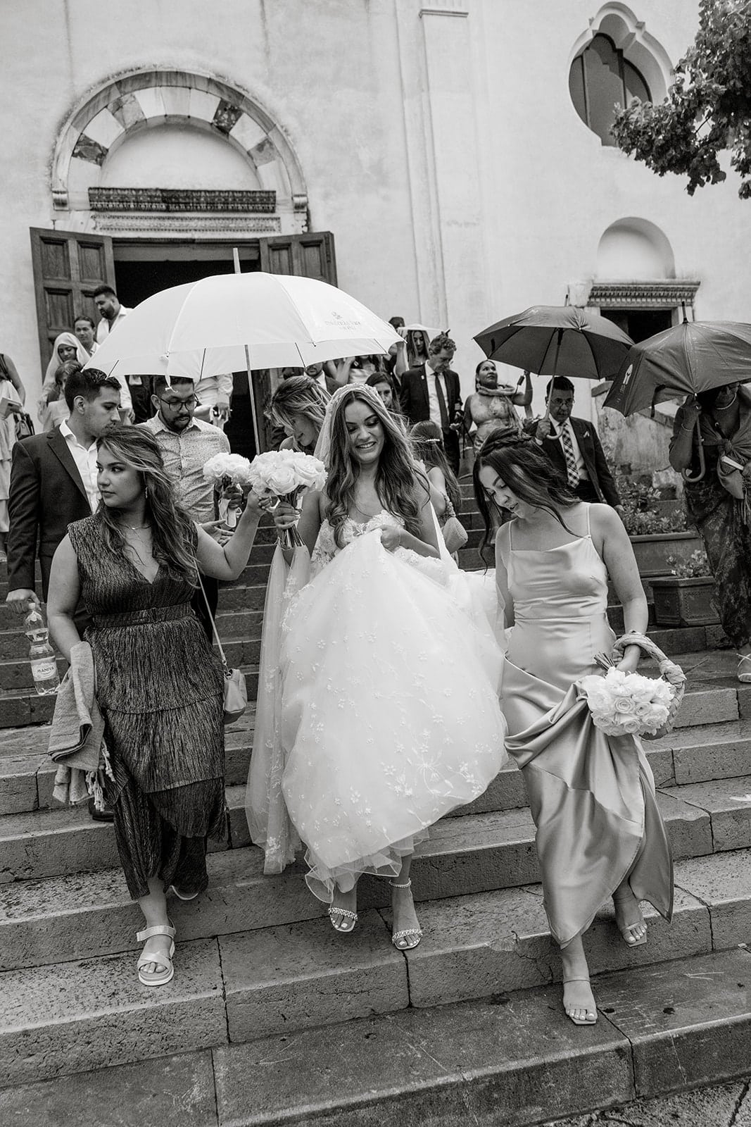 Bride and guests walk outside Ravello wedding venue in rain