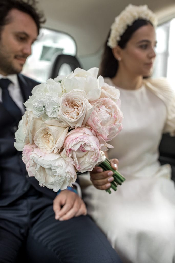 Peony bridal bouquet with bride and groom out of focus in the background