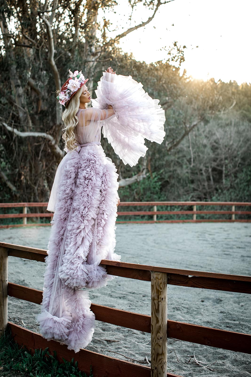 Model stands on fence railing in dramatic purple couture bridal robe