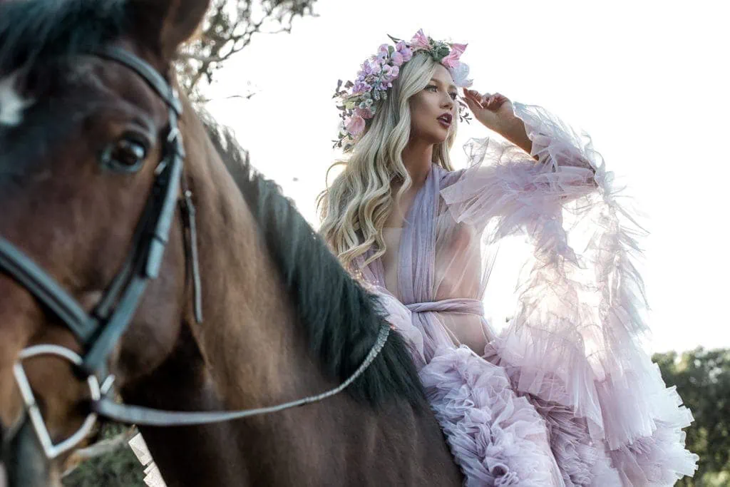 Model atop horse in purple luxury bridal robe for editorial session