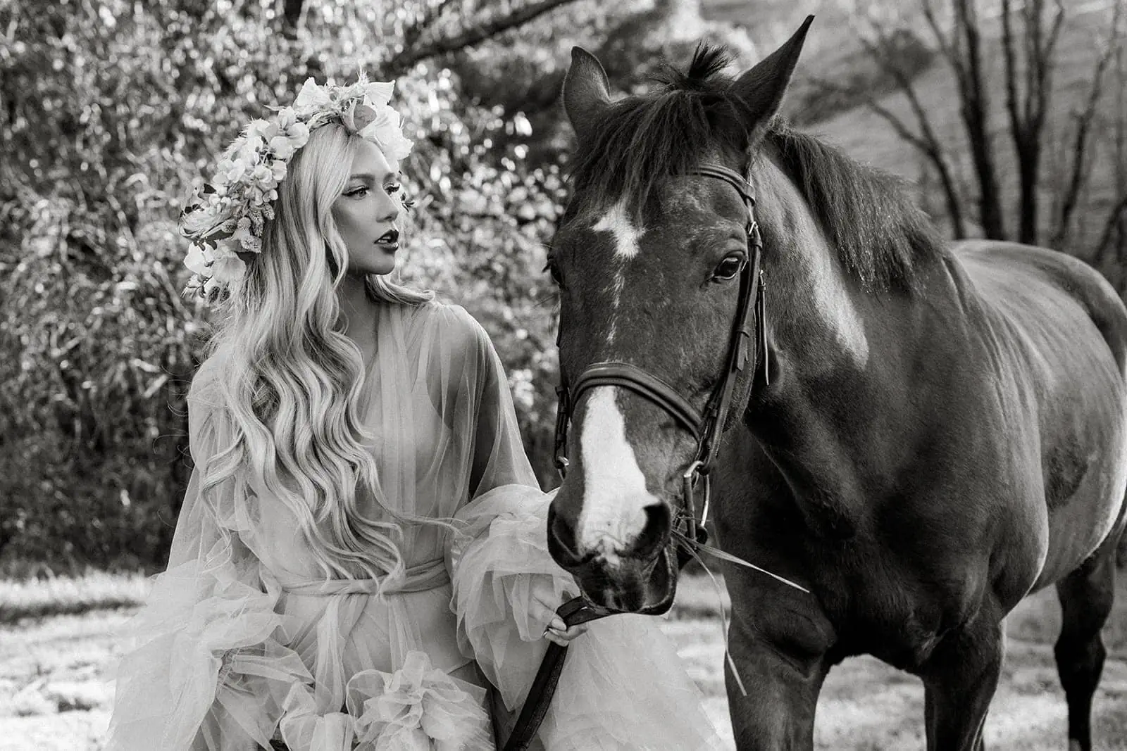 Model wears flower crown while stands next to horse 