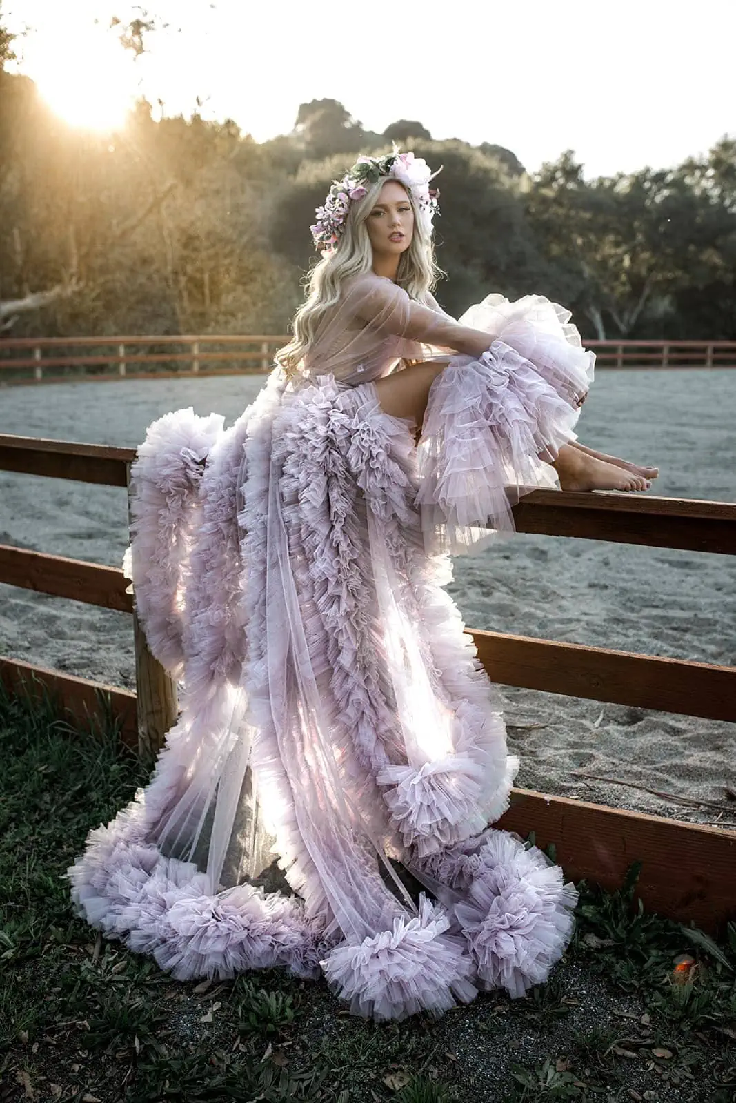 Model sits on fence railing wearing long luxury bridal robe