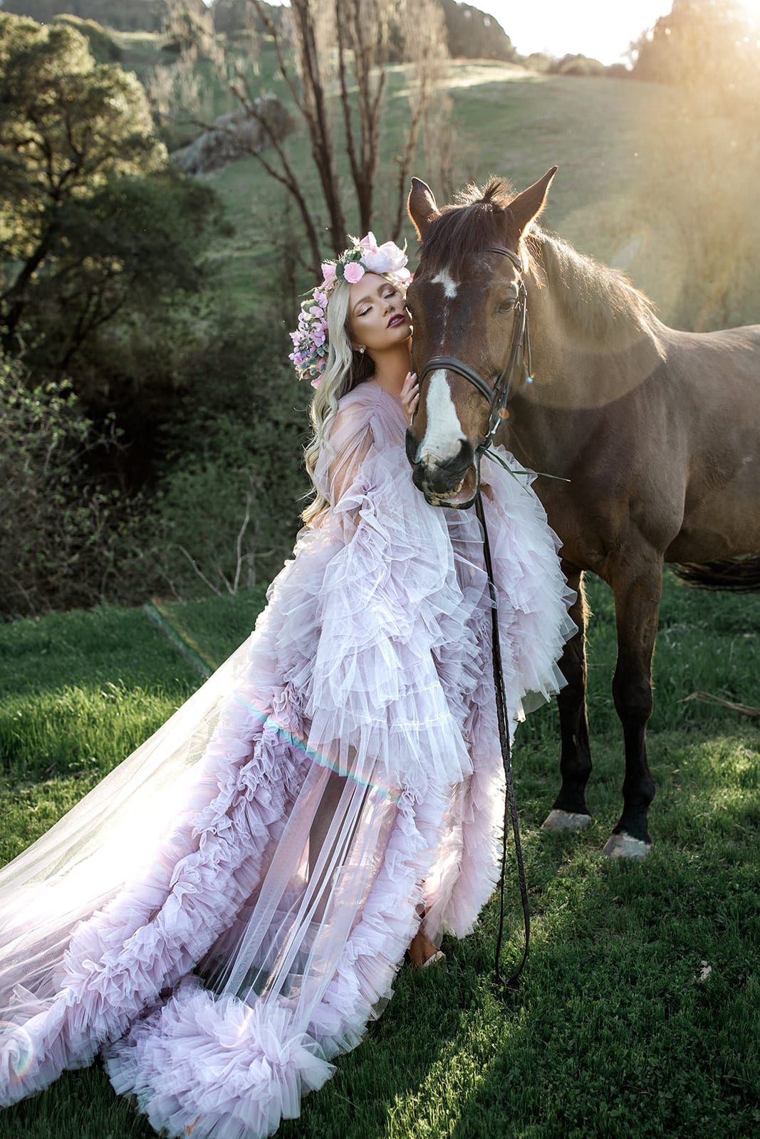 Model wearing tulle bridal robe stands next to horse