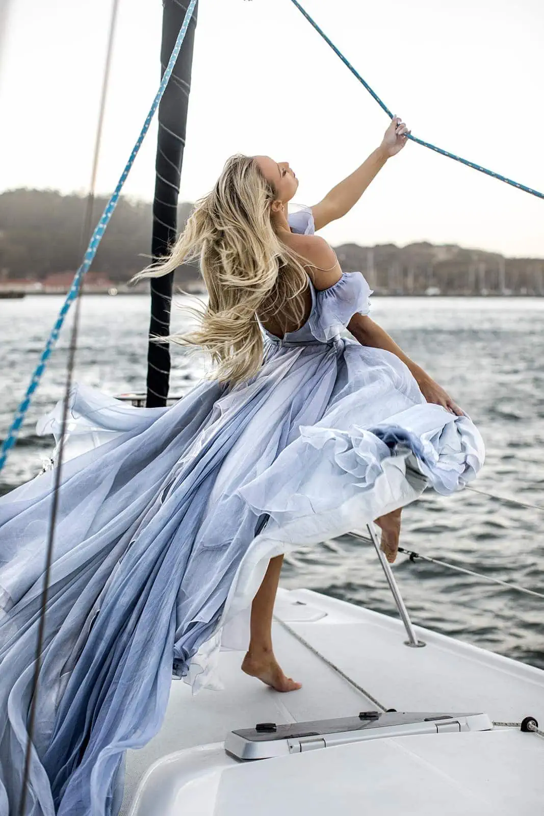 Woman stands on sailboat wearing Leanne Marshall gown