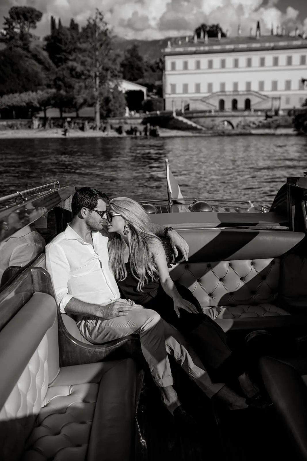 Man and woman on a riva boat on Lake Como with Italian villa in background