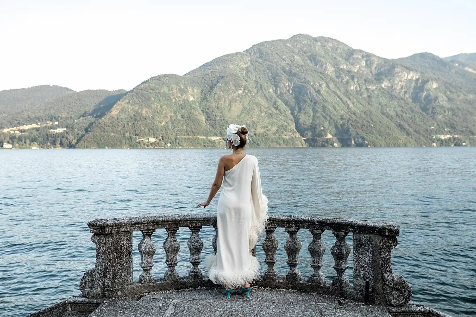 Bride stands near railing overlooking Lake Como