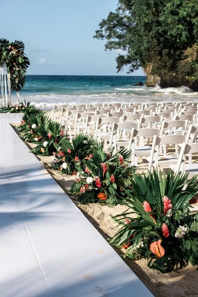 Floral arrangements line the aisles for a ceremony on the beach in Jamaica