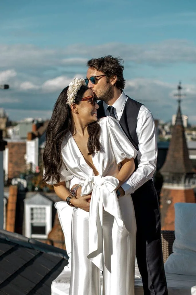 Groom kisses bride's forehead on London rooftop