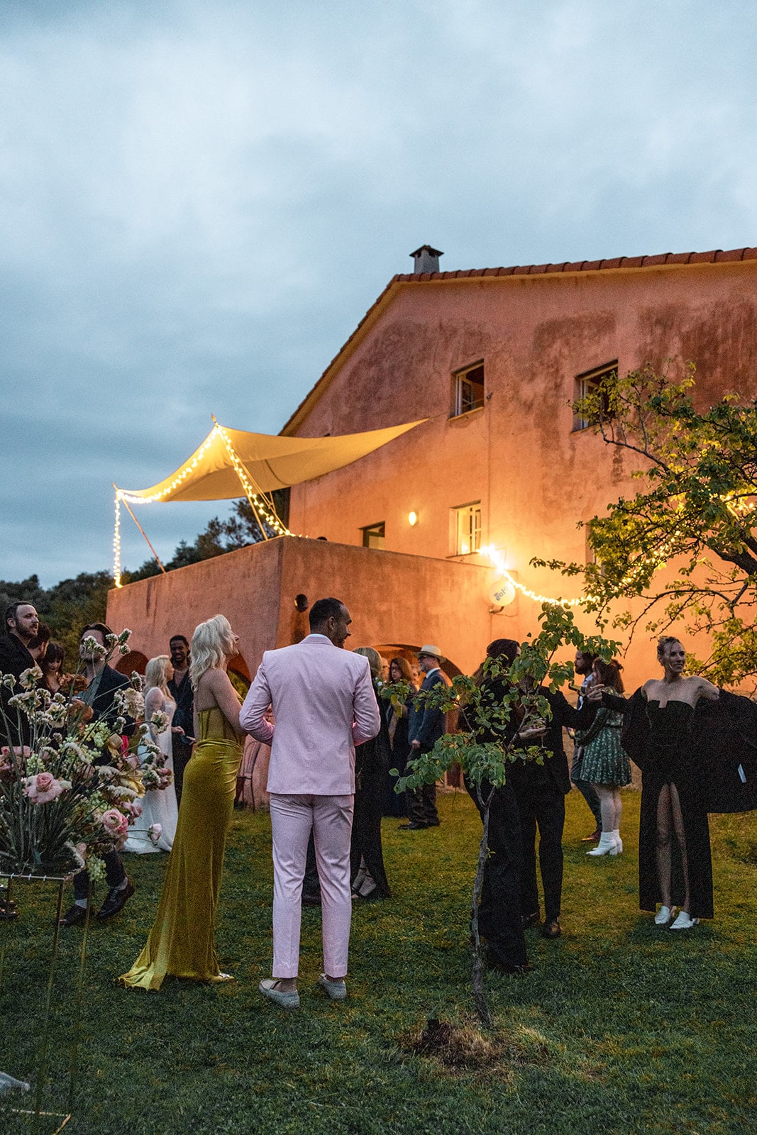 Guests gather outside Italian farmhouse for wedding reception
