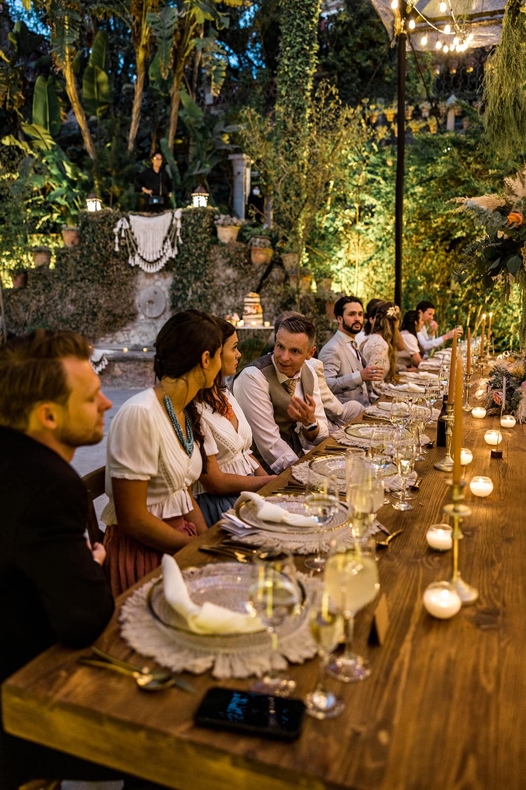 Families sit at banquet style table at wedding reception at Casa Hyder