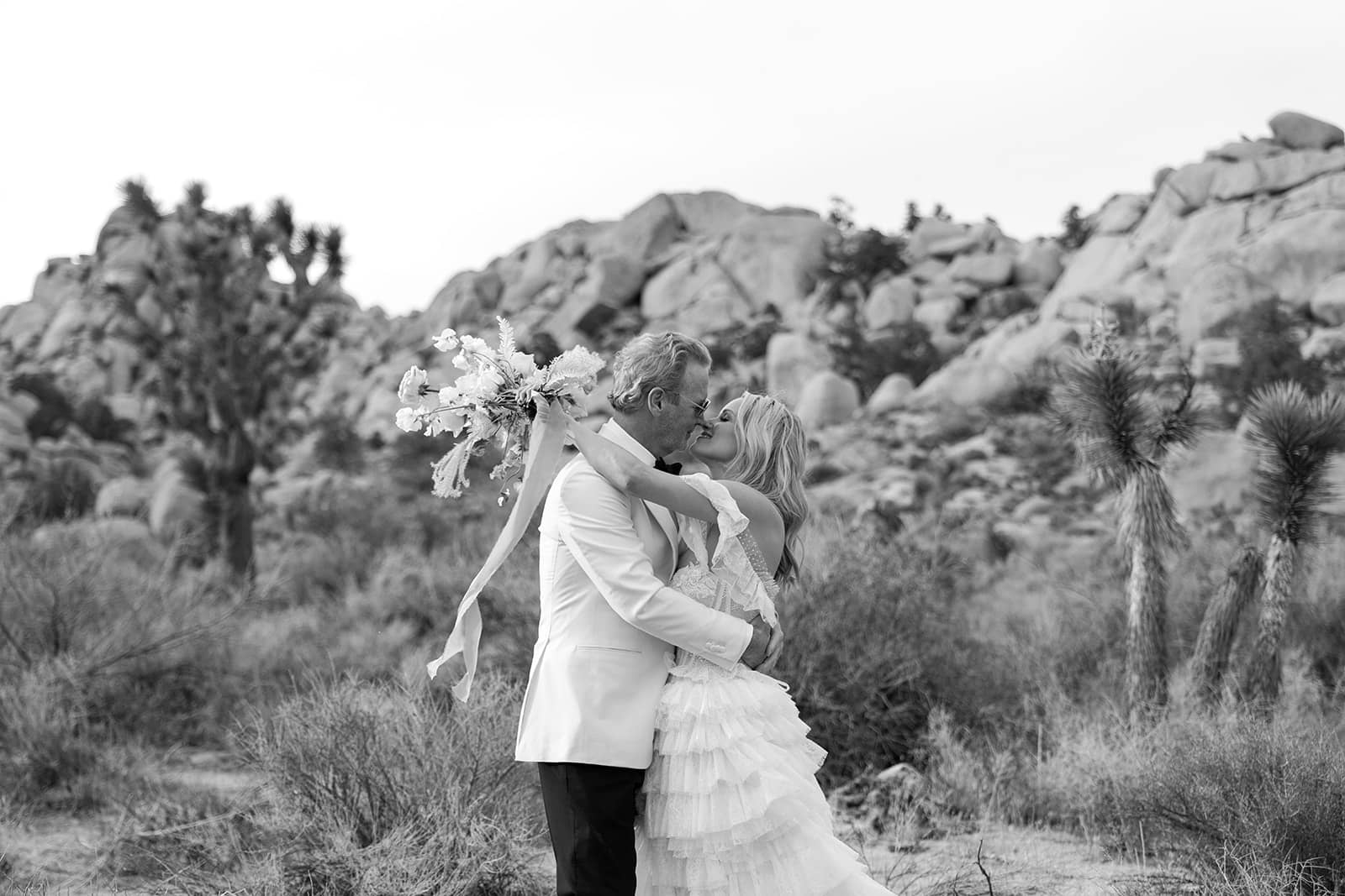 Bride and groom kiss in middle of Joshua Tree desert
