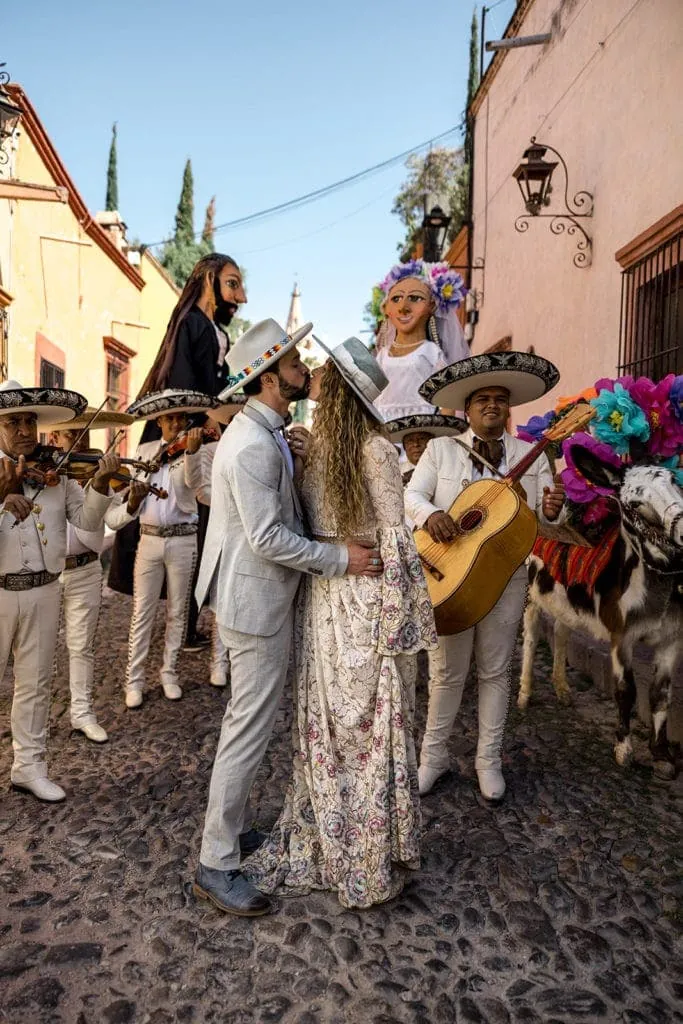 Bride and groom kiss while mariachi band plays in streets of Mexico