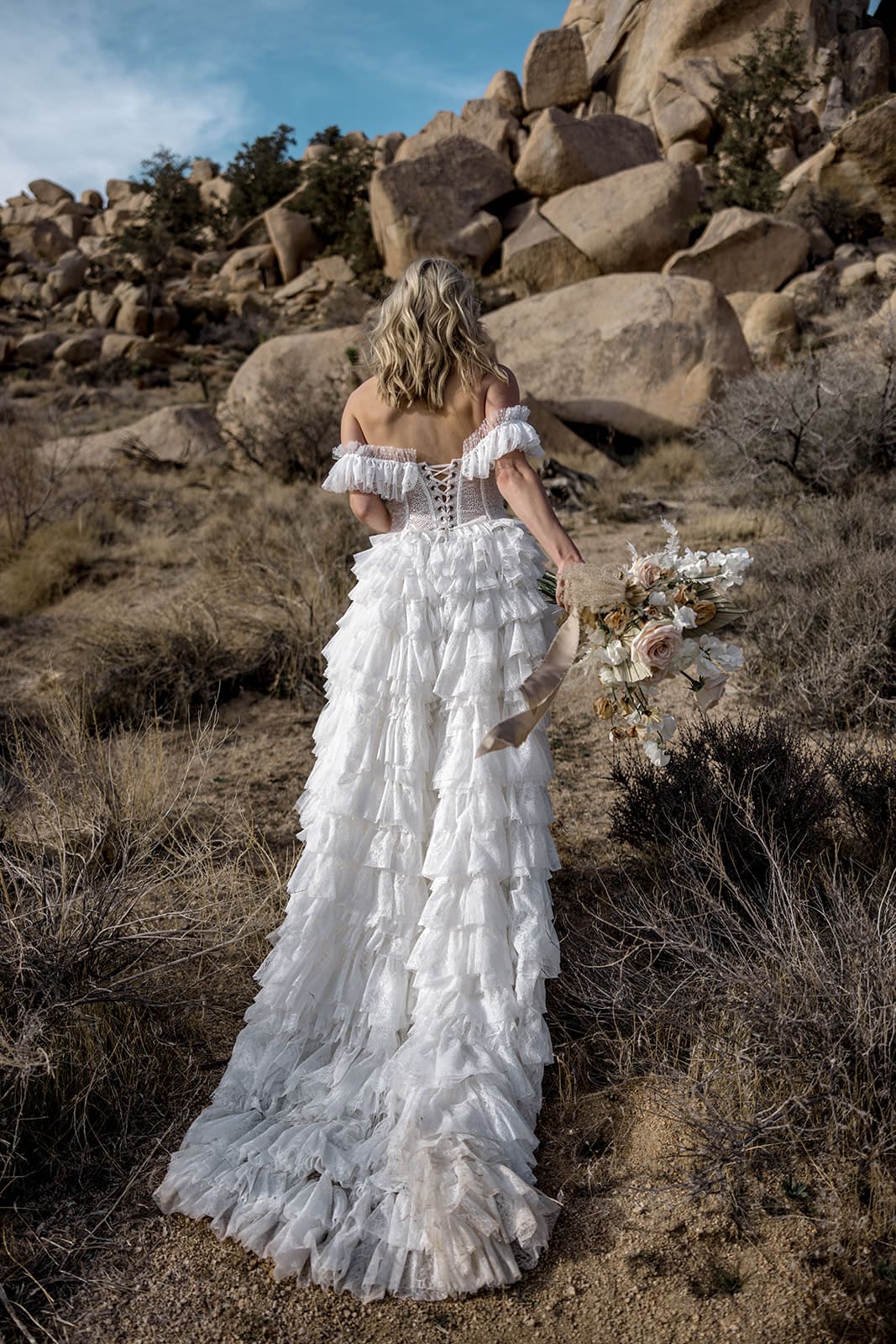 Bride wearing couture bridal gown walks in desert for elopement ceremony