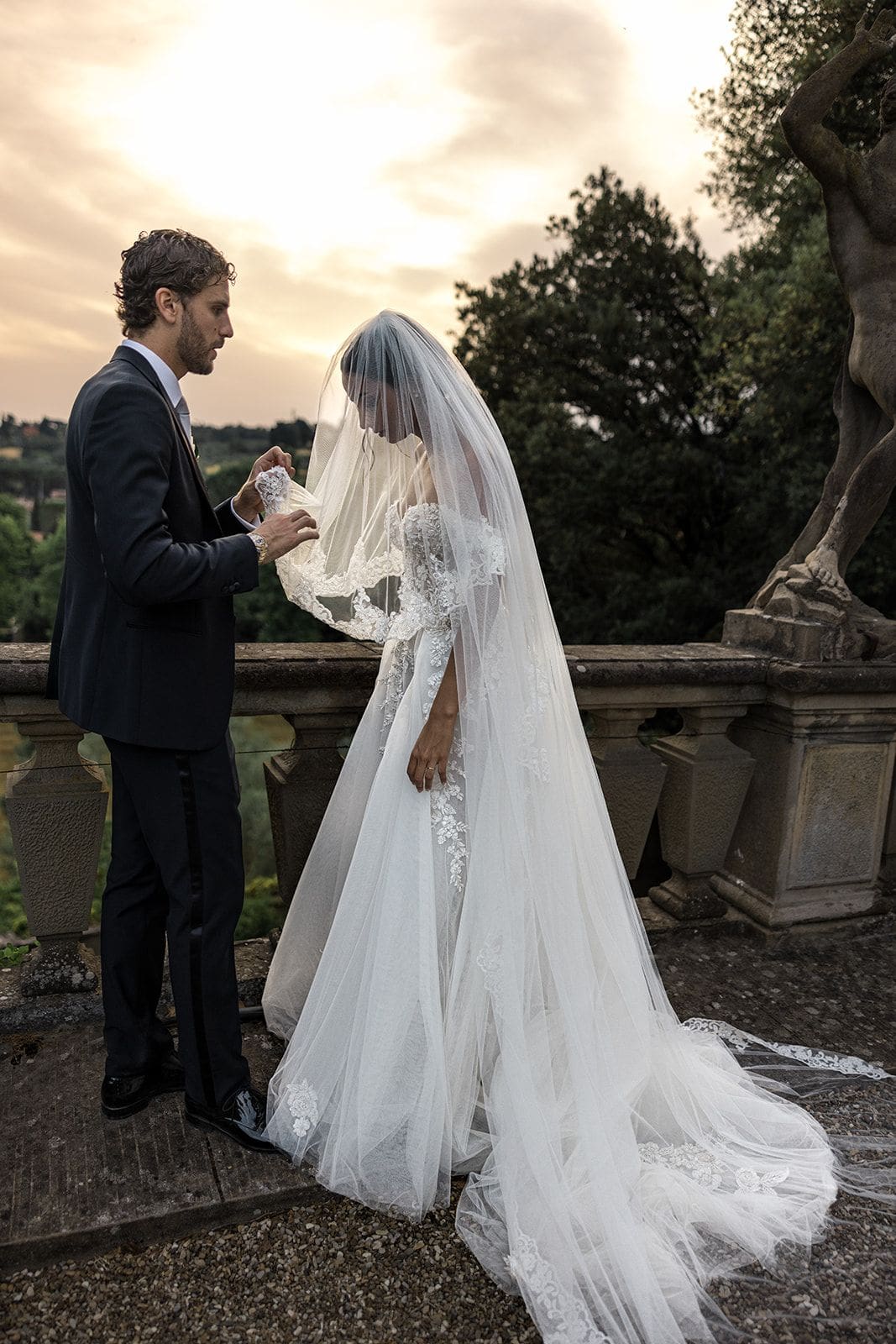 Groom lifts bride's veil outside of Fiesole wedding venue in Tuscany, Italy