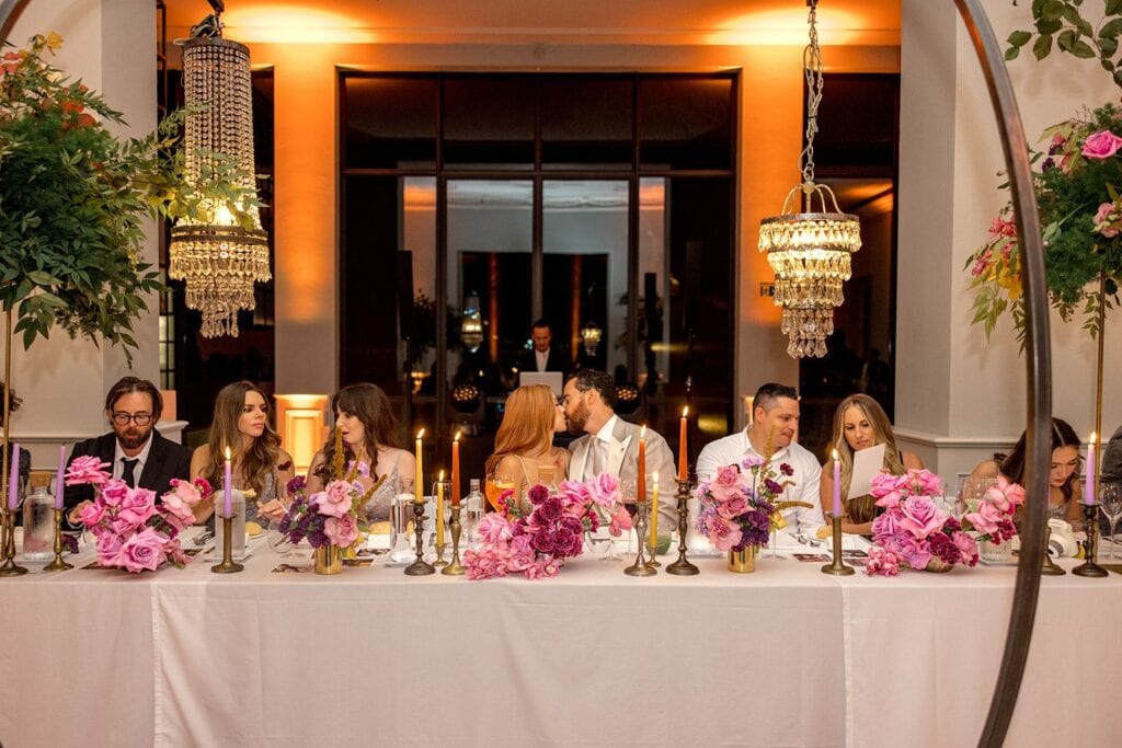 Bride and groom kiss at reception head table