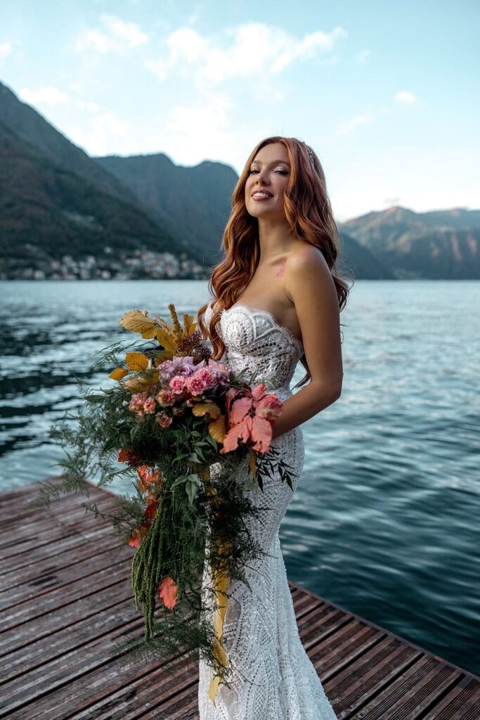 Bride waits to board a boat on Lake Como while holding her bridal bouquet