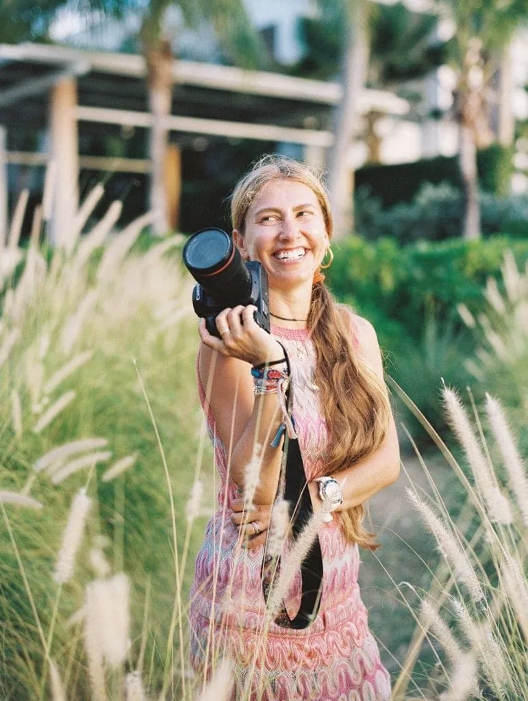 Woman smiling with camera as she photographs a wedding of ideal clients who asked all the right questions for wedding photographers before booking. 