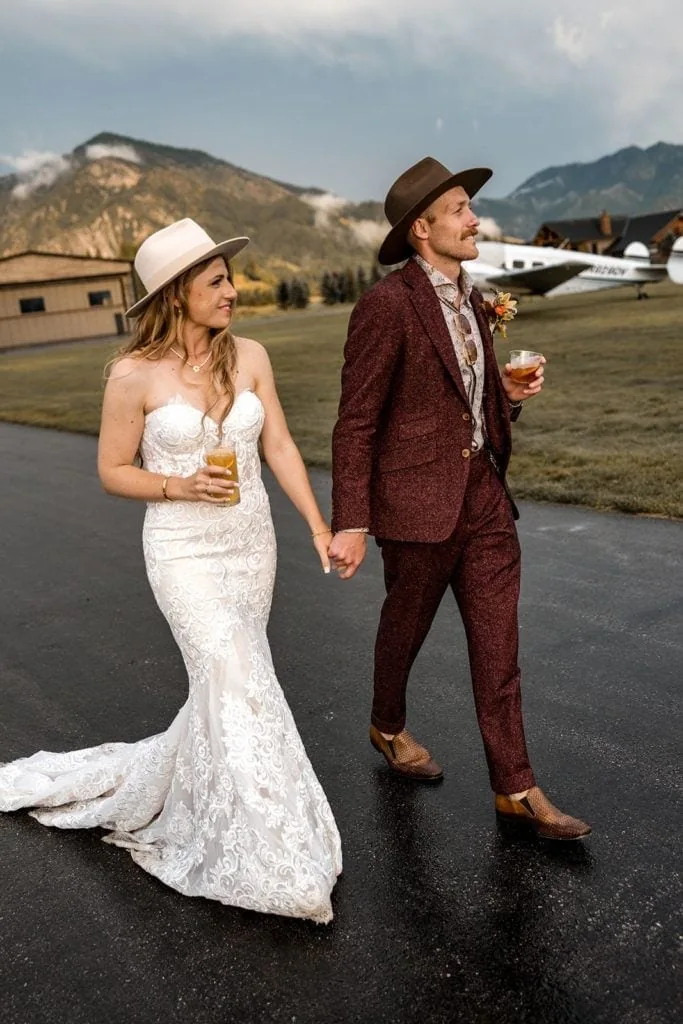 Bride and groom walk down a plane runway during their aviation themed wedding for couple's portraits