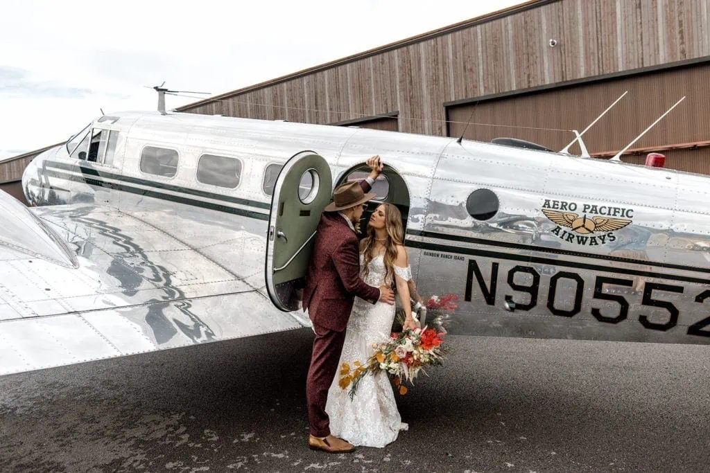 Bride and groom couple's portrait next to vintage airplane