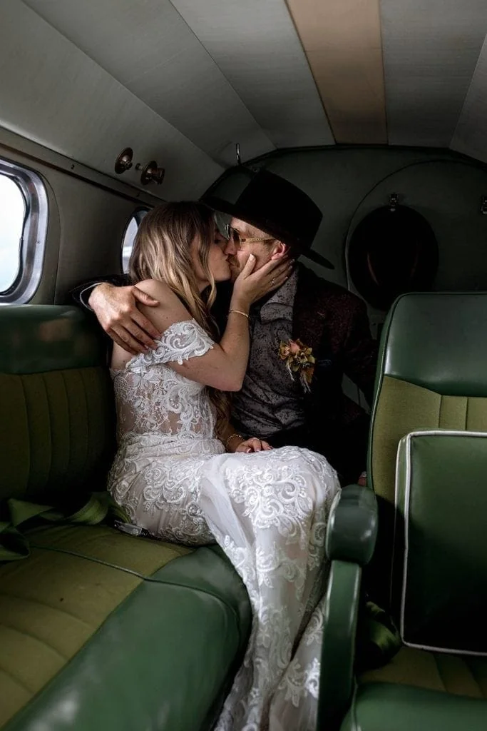 Bride and groom kiss during their first flight in a vintage airplane after wedding ceremony