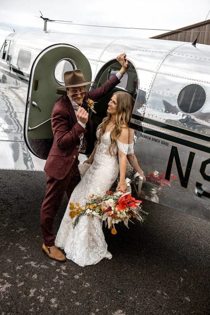 Bride and groom stand next to vintage airplane during couple's portraits
