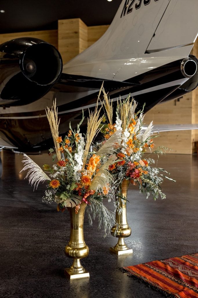 Floral arrangements in airplane hangar for wedding ceremony