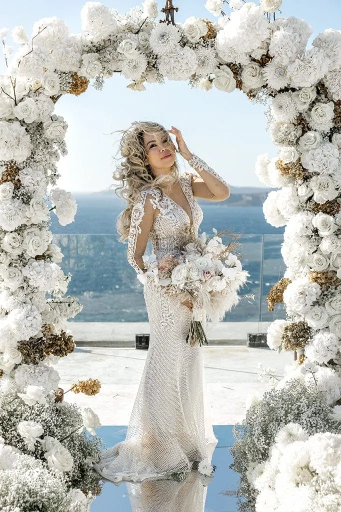 Bridal portrait under white flowers arch in Santorini wedding