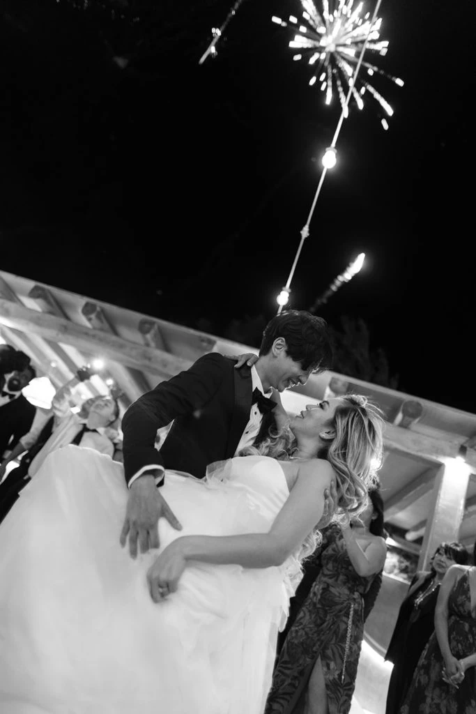 Bride and groom dance during reception with fireworks in the sky