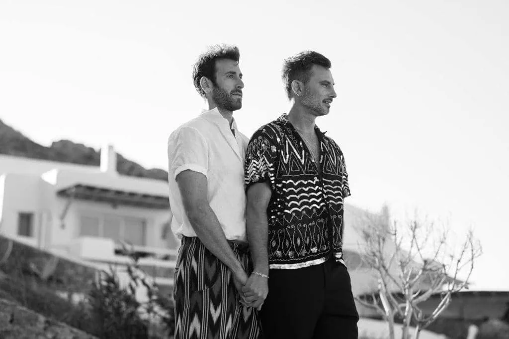 Two men holding hands during couple's portrait before Mykonos wedding