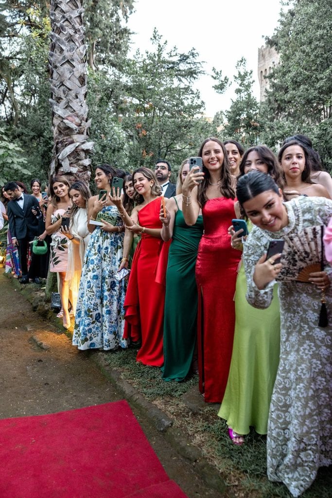 Wedding guests stand with their phones for the bride to walk down the aisle at the ceremony